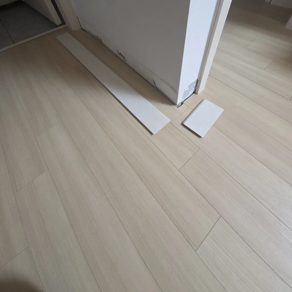 화성 몰딩교체 새 걸레받이 조각을 모서리 옆 바닥에 대어 둔 시공 장면